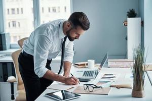 Handsome young man in shirt and tie working with documents in office photo