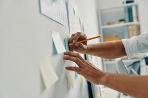 planificación de negocios. primer plano de un hombre escribiendo algo usando notas adhesivas mientras trabajaba en la oficina foto