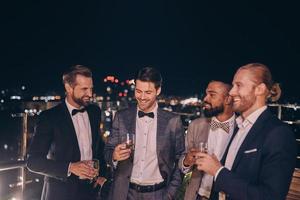 Group of handsome young men in suits and bowties drinking whiskey and smiling photo