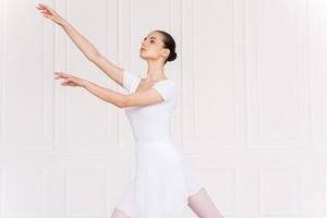 Graceful ballerina. Beautiful young ballerina in white tutu dancing in ballet studio photo