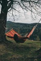Feel the freedom.  Beautiful young woman lying in hammock while relaxing on the valley under the tree photo