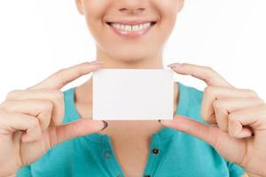 Woman with business card. Cropped image of young woman holding business card in her hand and smiling while standing isolated on white photo