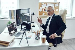Senior man in elegant business suit using modern technologies while making social media video photo