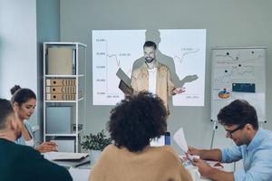 Group of young modern people in smart casual wear analyzing data on projection screen in the office photo