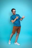 Handsome young man in casual clothing gesturing and smiling while standing against yellow background photo
