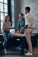 Group of young people in smart casual wear discussing business while working in the office photo