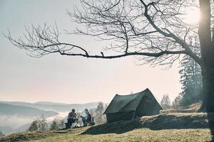 Breathtaking landscape. Young couple having morning coffee while camping in mountains photo