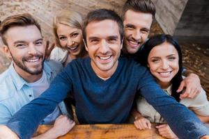 Funny selfie with friends. Top view of five cheerful young people making selfie and smiling while standing outdoors photo