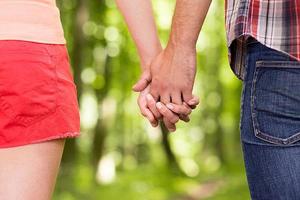Couple holding hands. Close-up of man and woman holding hands while walking in the park photo