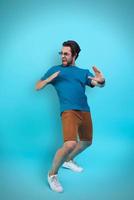 Excited young man in casual clothing gesturing while standing against yellow background photo