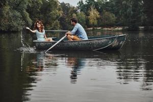 Feeling playful. Beautiful young couple enjoying romantic date while rowing a boat photo