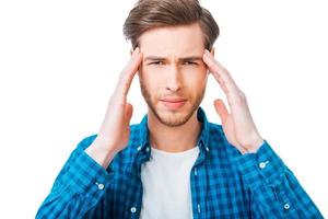 Feeling exhausted. Frustrated young man touching his head while standing against white background photo