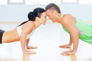 Fit couple. Man and woman doing push-up looking to each other photo