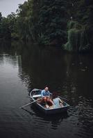 Getting away from... Top view of beautiful young couple feeding ducks while rowing a boat photo