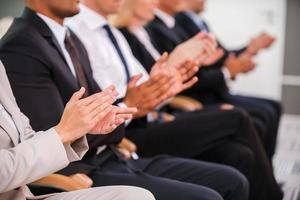 Great success. Group of business people clapping hand while sitting in a row photo