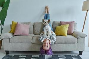 Happy teenage girl carrying her little dog while relaxing on the couch at home photo