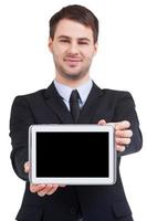 Advertising your product. Cheerful young man in formalwear showing his digital tablet while standing isolated on white photo