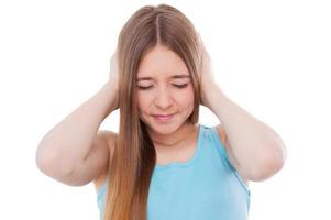 Too loud sound. Teenage girl covering ears with hands and keeping eyes closed while standing isolated on white photo
