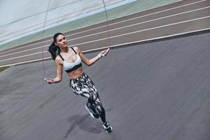 empujando duro para ganar. vista superior de una hermosa joven con ropa deportiva saltando la cuerda mientras hace ejercicio al aire libre foto