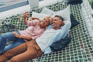 vista superior de una hermosa pareja madura haciendo selfie por teléfono inteligente y sonriendo foto