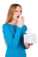mujer estornudando. mujer joven sosteniendo un pañuelo cerca de la cara y estornudando mientras está aislada en blanco foto