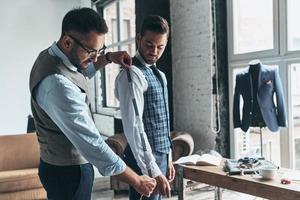 dos jóvenes hombres de moda midiendo chaquetas foto