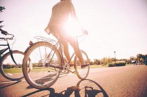 On the way to sunrise. Low angle view of young man riding bicycle together with his friends along the road photo