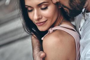 Moments of intimacy. Handsome young man embracing his beautiful girlfriend while spending time together in the city photo