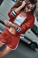 Enjoying her sports style. Beautiful young woman in sport clothing keeping hand in hair while standing outdoors photo