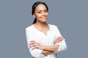 confiado en su belleza. retrato de una atractiva joven africana con los brazos cruzados y sonriendo mientras se enfrenta a un fondo gris foto