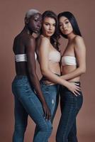 Free your fabulosity. Full length of three attractive young women looking at camera while standing against brown background photo