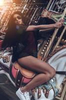 Just having fun. Attractive young mixed raced woman in red bikini riding merry-go-round photo