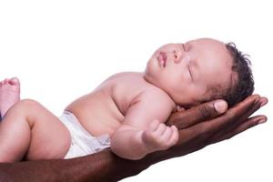 Ángel durmiente. vista lateral de las manos negras que sostienen al pequeño bebé lindo contra el fondo blanco foto
