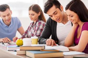 Confident students. Four cheerful students studying together while sitting at the desk photo