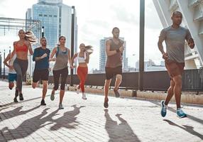 Full length of people in sports clothing jogging while exercising on the sidewalk outdoors photo