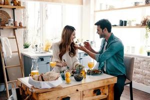 hermosa pareja joven disfrutando de un desayuno saludable mientras se sienta en la cocina en casa foto