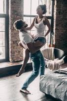 Enjoying every moment together. Young passionate couple having fun together and looking happy while handsome young man carrying his girlfriend on shoulders photo