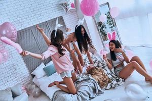 No rules for them. Playful young women in bunny ears having fun and smiling while enjoying home party photo