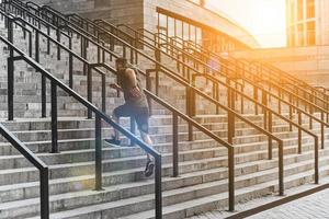 Pushing hard to win. Full length of young man in sport clothing running up the stairs while exercising outside photo