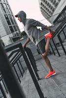 Relaxing exercise. Full length of young man in sports clothing warming up while exercising outdoors photo