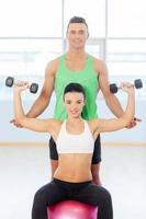 Young couple exercising at the fitness gym. Woman in gym with personal fitness trainer exercising photo