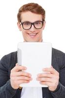 Wow Cheerful young man looking at digital tablet and expressing positivity while standing isolated on white photo