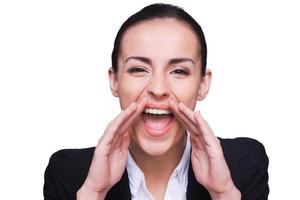 Announcing good news. Happy young woman in formalwear looking at camera and shouting while standing isolated on white photo