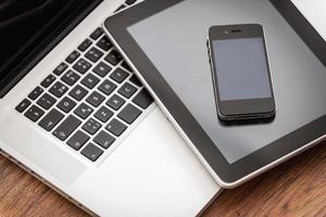 Smart helpers for good business. Close-up of laptop with digital tablet and mobile phone laying on the wooden desk photo