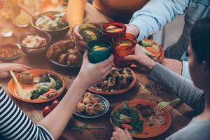 nos saluda la vista superior de la gente animando con bebidas mientras se sienta en la mesa de comedor rústica foto