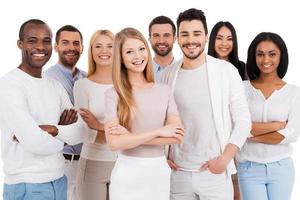 Positive professional team. Group of positive and diverse people in smart casual wear looking at camera and smiling while standing against white background photo