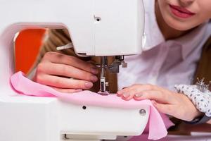 diseñador de moda en el trabajo. primer plano de una diseñadora de moda que trabaja en una máquina de coser mientras está sentada en su lugar de trabajo foto