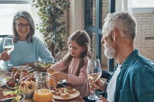 Happy multi-generation family communicating and smiling while having dinner together photo