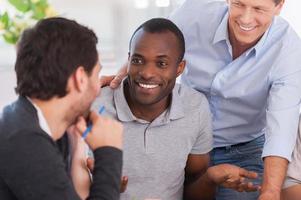 Hot office discussion. Group of cheerful business people sitting together at the table and discussing something photo