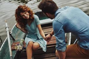 mejor cita nunca. feliz pareja joven preparándose para remar un bote mientras disfruta de su cita al aire libre foto